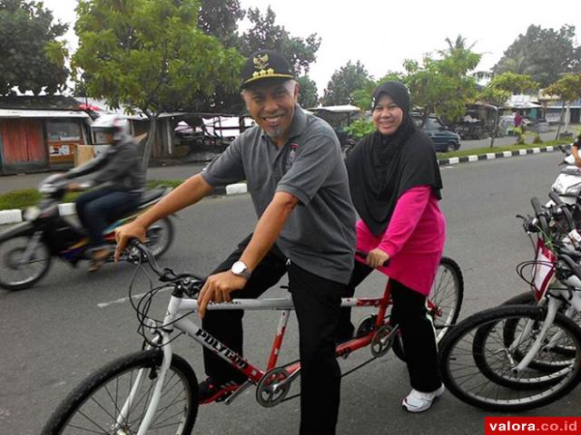 Wako Padang, Mahyeldi bersama istri, Harneli Mahyeldi, mencoba sepeda cinta yang disewakan sejumlah pedagang di kawasan Pantai Padang, Minggu (5/4/2015) usai peringatan hari nelayan internasional. (foto humas pemko)