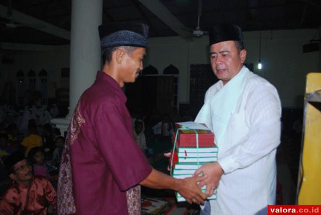 Bupati Pessel, Nasrul Abit menyerahkan bantuan al Quran kepada seorang pengurus masjid saat Safari Ramadhan 1435 H lalu. (Humas Pemkab Pessel)