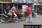 Pemilik Abyan Gemstone, Ronal (baju merah) membagikan masker pada pengendara yang lewat di depan warungnya, di Jl Alai-Bypass, Jumat (23/10/2015) siang. (istimewa)
