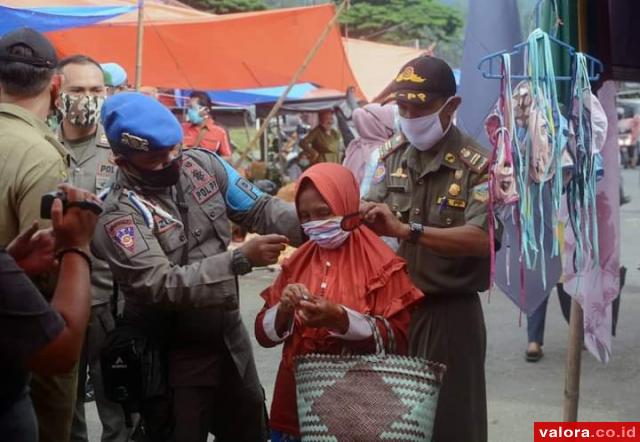 Kepala Satuan Polisi Pamong Praja (SatPol PP) Epli Rahmat memasangkan masker pada warga di Pasar Modern Padang Aro, Rabu (16/9/2020). (humas)