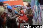 Kepala Satuan Polisi Pamong Praja (SatPol PP) Epli Rahmat memasangkan masker pada warga di Pasar Modern Padang Aro, Rabu (16/9/2020). (humas)