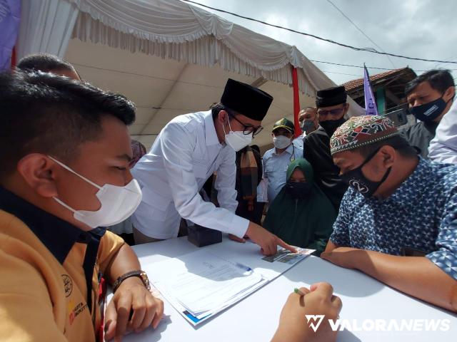 Wali Kota Bukittinggi, Erman Safar meneliti berkas pengajuan pinjaman modal kerja dari seorang pedagang, saat peluncuran Tabungan Utsman oleh BPRS Jam Gadang, di jalan di bawah Jembatan Gatuang, Pasar Bawah, Rabu pagi. (hamriadi)
