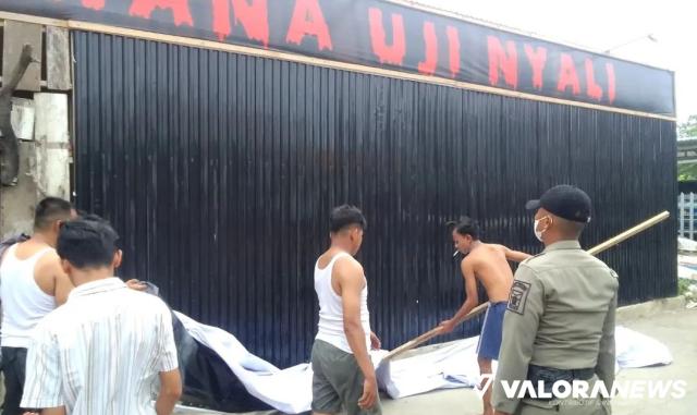 Personel Satpol PP Padang mengawasi proses penurunan spanduk wahana uji nyali yang sebagian kata-katanya tak pantas, Jumat sore. (humas)