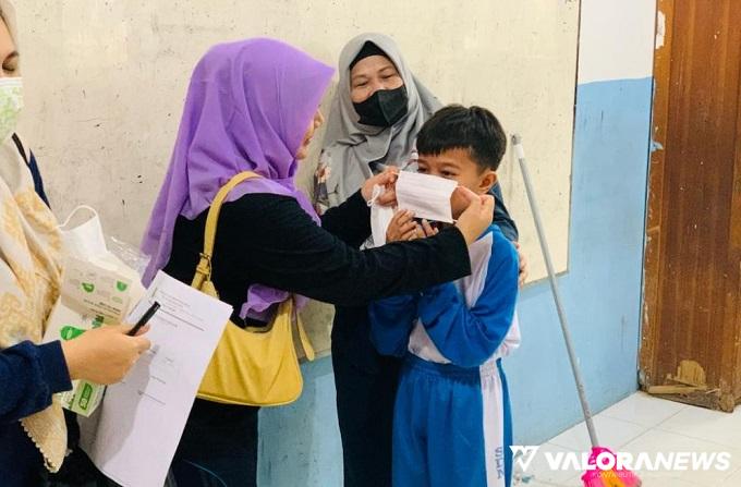 Siswa sebuah sekolah dipasangkan masker yang benar oleh gurunya. (humas)