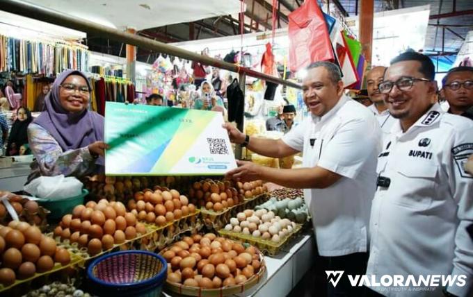 Wamenaker, Afriansyah Noor didampingi Bupati Tanah Datar, Eka Putra saat menyerahkan kartu peserta BPU BPJS Ketenagakerjaan pada pedagang Pasar Batusangkar, Rabu. (irfan taufik)