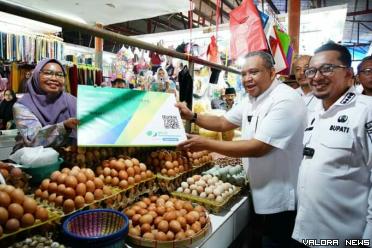 Wamenaker, Afriansyah Noor didampingi Bupati Tanah Datar, Eka Putra saat menyerahkan kartu peserta BPU BPJS Ketenagakerjaan pada pedagang Pasar Batusangkar, Rabu. (irfan taufik)