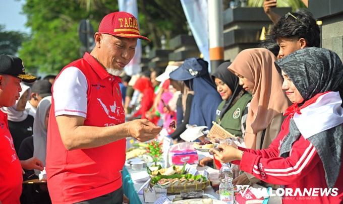 Gubernur Sumbar, Mahyeldi menikmati sajian Lamang Tapai usai membuka Festival Kuliner Minangkabau dan Senam Bersama di salah satu ruas jalan utama di Kota Padang, Ahad. Lamang Tapai merupakan kuliner khas daerah kelahiran Mahyeldi, Kamang. (humas)