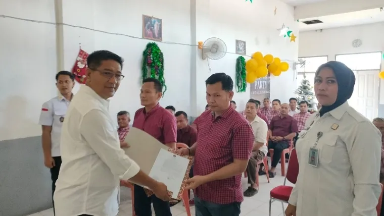 Kepala Lapas Padang, Junaidi Rison menyerahkan surat keputusan remisi pada perwakilan warga binaan dalam perayaan natal sederhana yang digelar di Gereja Lapas Padang, Rabu. Acara ini dihadiri pejabat struktural dan jajaran Lapas Padang. (veri rikiyanto)