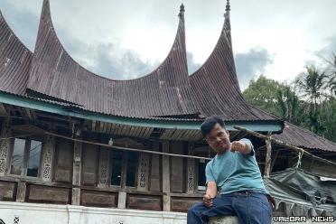 Penggiat Satuan Tenaga Konselor Kepariwisataan (SANAK) Sumatera Barat, Muhammad Fadhli dengan latar belakang rumah gadang Minang khas Simpang Sugiran yang tak seperti lazimnya rumah adat Minang. (istimewa)