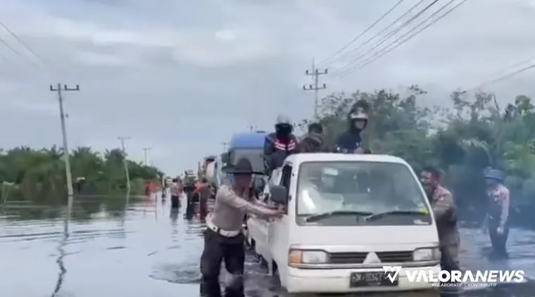 Petugas Satlantas Polres Pelalawan membantu mendorong mobil yang mogok di KM 83 Jalan Lintas Timur (Jalintim), di Kecamatan Pangkalan Kuras, Kabupaten Pelalawan, Jumat siang. (humas)
