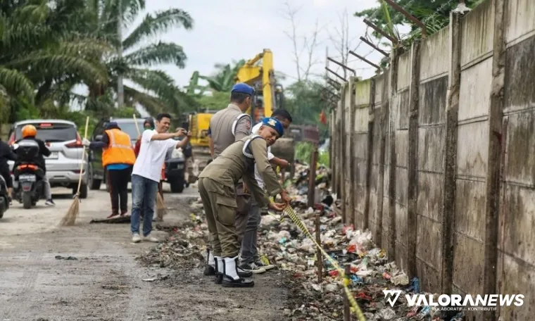 Personel Satpol PP Pekanbaru memasang tanda larangan membuang sampah di salah satu bahu jalan, Jumat. (humas)