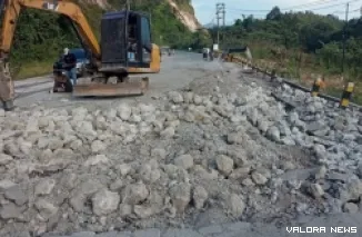 Pekerja tengah memperbaiki jalan yang rusak di kilometer 106-107 dan di dekat gerbang perbatasan Sumbar dan Riau. (humas)