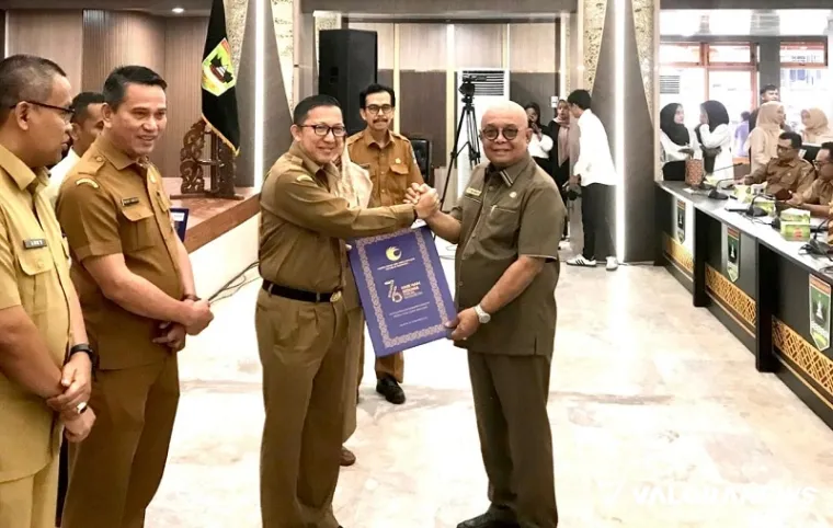 Sekdaprov Sumar, Yozawardi Usama Putra serahkan penghargaan sebagai kabupaten/kota peduli HAM Tahun 2025 pada Sekda Agam, Edi Busti disela rapat Forum Perangkat Daerah di aula kantor gubernur Sumbar, di Padang, Selasa. (humas)