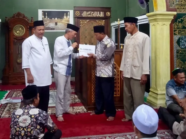 Sekdakab Pessel Mawardi Roska menyerahkan bantuan Rp 15 juta ke Masjid Imaduddin, Simpang Ampang Pulai,  Kecamatan Koto XI Tarusan, Kamis (20/3/2025). FOTO: Dok Balai Jurnalis Kabupaten Pesisir Selatan
