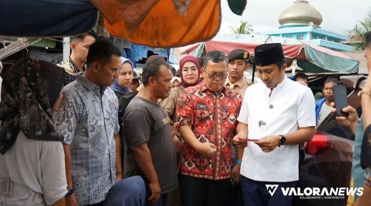 Wagub Sumbar, Vasko Ruseimy memeriksa uang palsu pecahan Rp100 ribu yang diterimanya dari pedagang sayur di Pasar Bandar Buat, Kamis. (humas)