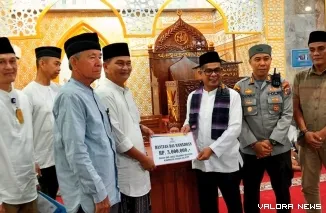 Wakil Bupati Risnaldi, memberikan bantuan Baznas kepada Marwan Anas, pengurus Masjid Raya Nurul Ulum Barung Barung Balantai, Kecamatan Koto XI Tarusan, Jumat (21/3/2025). FOTO: tusrisep