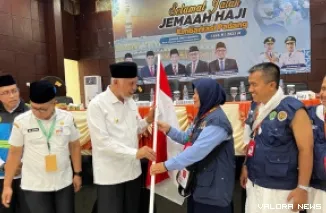 Gubernur Sumbar, Mahyeldi menyerahkan pataka Sumbar pada pembimbing haji Kloter 14 Embarkasi Padang, Rabu. (humas)