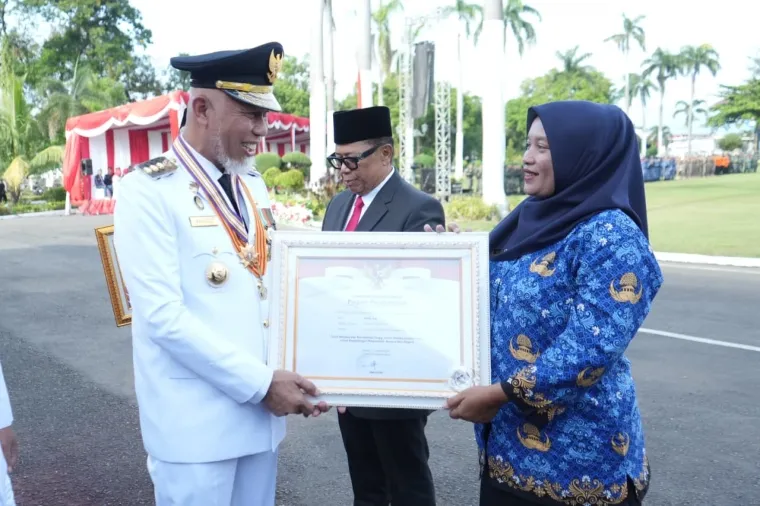 Gubernur Sumbar, Mahyeldi menyerahkan penghargaan pada Bidan Dona Lubis atas dedikasinya pada profesi usai perayaan HUT RI Ke-80 di halaman istana gubernur, Ahad. (humas)
