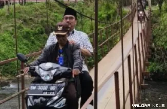 Anggota Fraksi Partai Golkar DPR RI Dapil Sumbar II, Benny Utama diboncengi warga dengan sepeda motor, melewati jembatan rajang, saat reses perorangan masa persidangan IV Tahun 2024-2025 di daerah terluar dan terdepan di Kabupaten Pasaman. (istimewa)