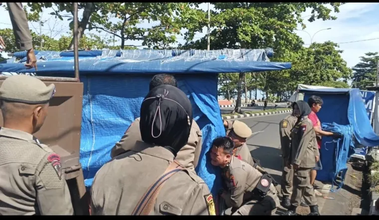 Satpol PP Padang menertibkan lapak dagangan PKL di Pantai Padang, Senin (13/10/2025)