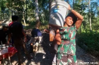 Puluhan prajurit TNI berseragam loreng kompak memanggul ember berisi material cor di pundak