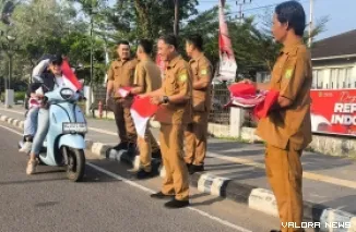 Kepala Disnakertrans Muba, Herryandi Sinulingga AP dan jajaran, bagikan bendera pada pengendara yang lewat di depan kantor. (toyipa)
