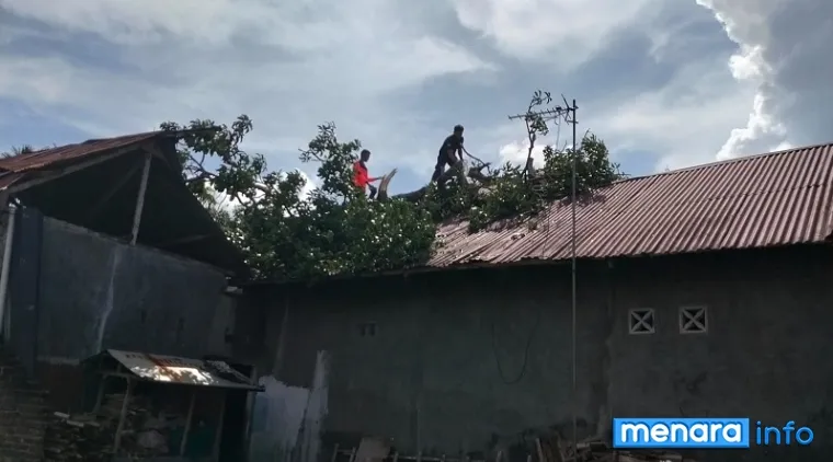 Personel BPBD Padang bersama aparat kelurahan, membersihkan ranting dan dahan kayu yang roboh akibat hujan disertai badai, Kamis malam. (humas)