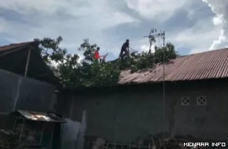 Personel BPBD Padang bersama aparat kelurahan, membersihkan ranting dan dahan kayu yang roboh akibat hujan disertai badai, Kamis malam. (humas)