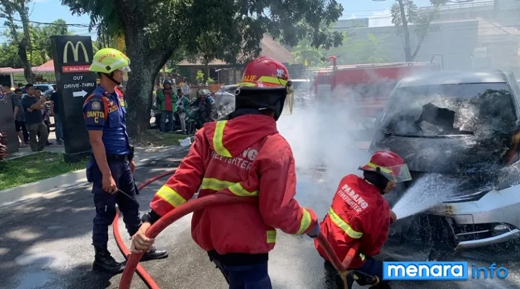 Petugas pemadam tengah berusaha memadamkan api yang memercik dari kap mobil Honda Fred saat melintas di Jl A Yani (Depan Resto McD), Jumat siang. (humas)