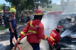 Petugas pemadam tengah berusaha memadamkan api yang memercik dari kap mobil Honda Fred saat melintas di Jl A Yani (Depan Resto McD), Jumat siang. (humas)