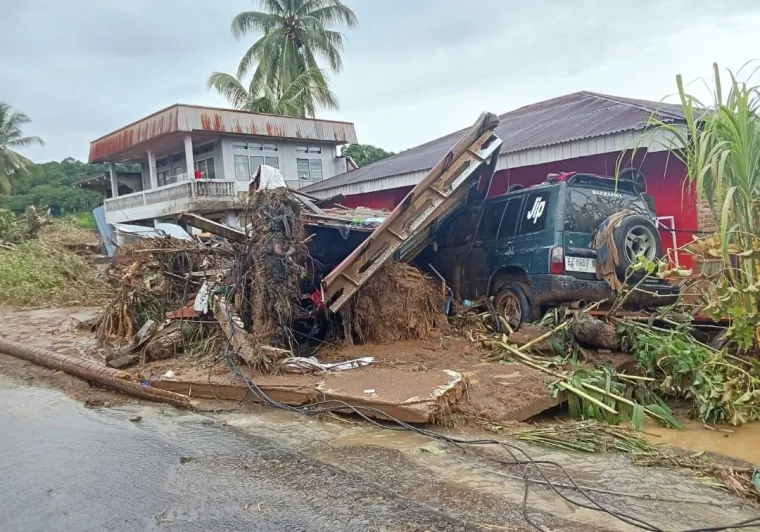Terlihat sebuah rumah warga dan satu unit kendaraan rusak akibat material kayu dan lumpur dibawa arus banjir bandang. Foto Anizur
