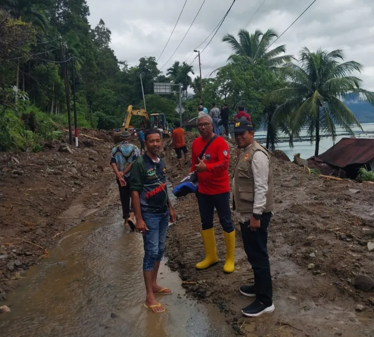Beberapa petugas berdiri di badan jalan Muko-muko yang telah bisa dilalui, setelah pembersihan material galodo dilakukan secara bersama-sama. Foto Anizur.