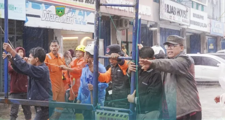 Wako Hendri Arnis ketika bersama warga dan petugas lainnya menahan tiang reklame di depan Masjid Taqwa Muhammadiyah agar tidak roboh. Foto istimewa.