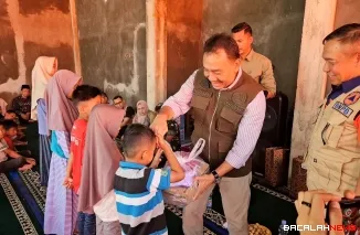 Wakil Bupati Agam, H. Muhammad Iqbal, S.E., M.Com terlihat menyerahkan bantuan seragam sekolah bagi anak korban bencana hidrometeorologi di Kabupaten Agam. Foto Anizur